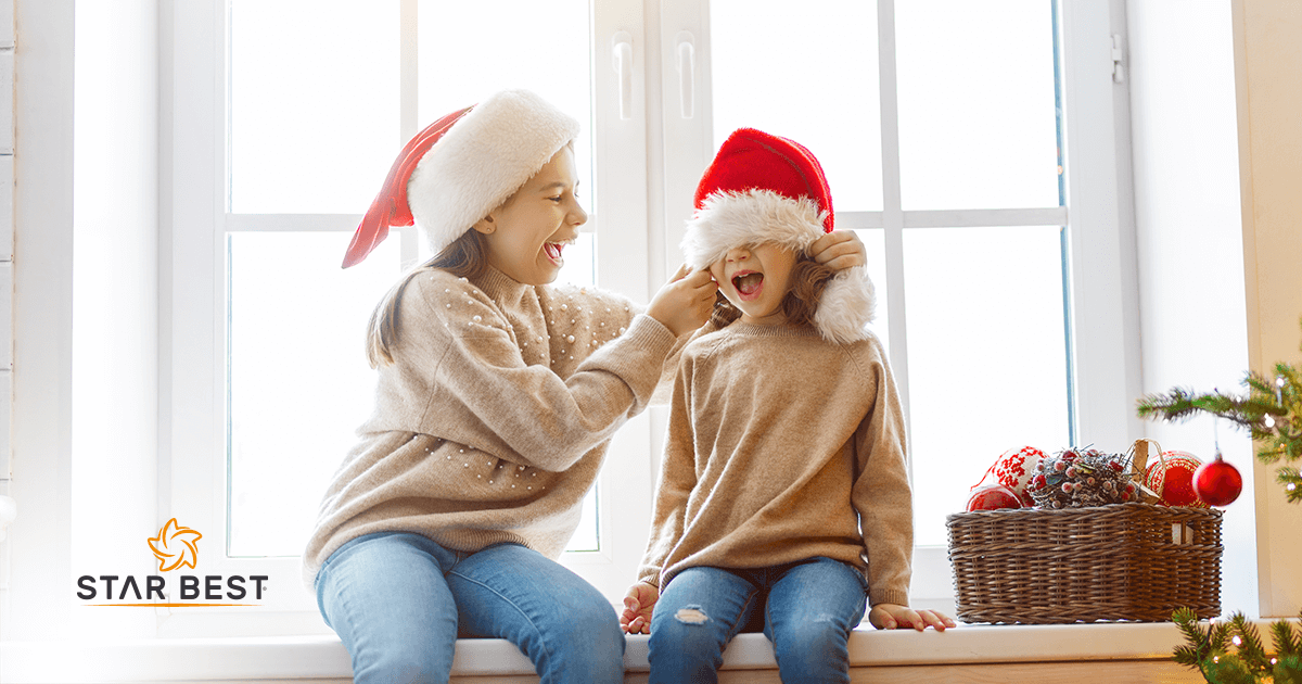 Sugestões de roupas infantis para o natal - na imagem há duas crianças, meninas com gorro de natal vermelho.